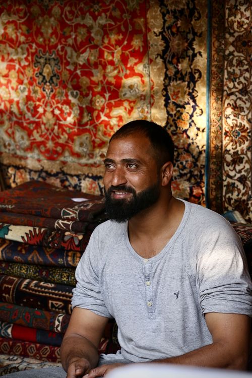 Middle Eastern Man Surrounded by Colorful Rugs · Free Stock Photo