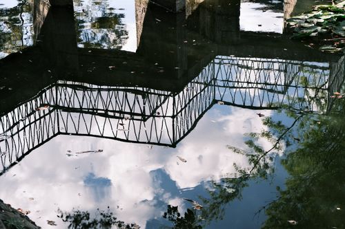 Free A serene reflection of a bridge and sky in still water, creating a tranquil scene. Stock Photo