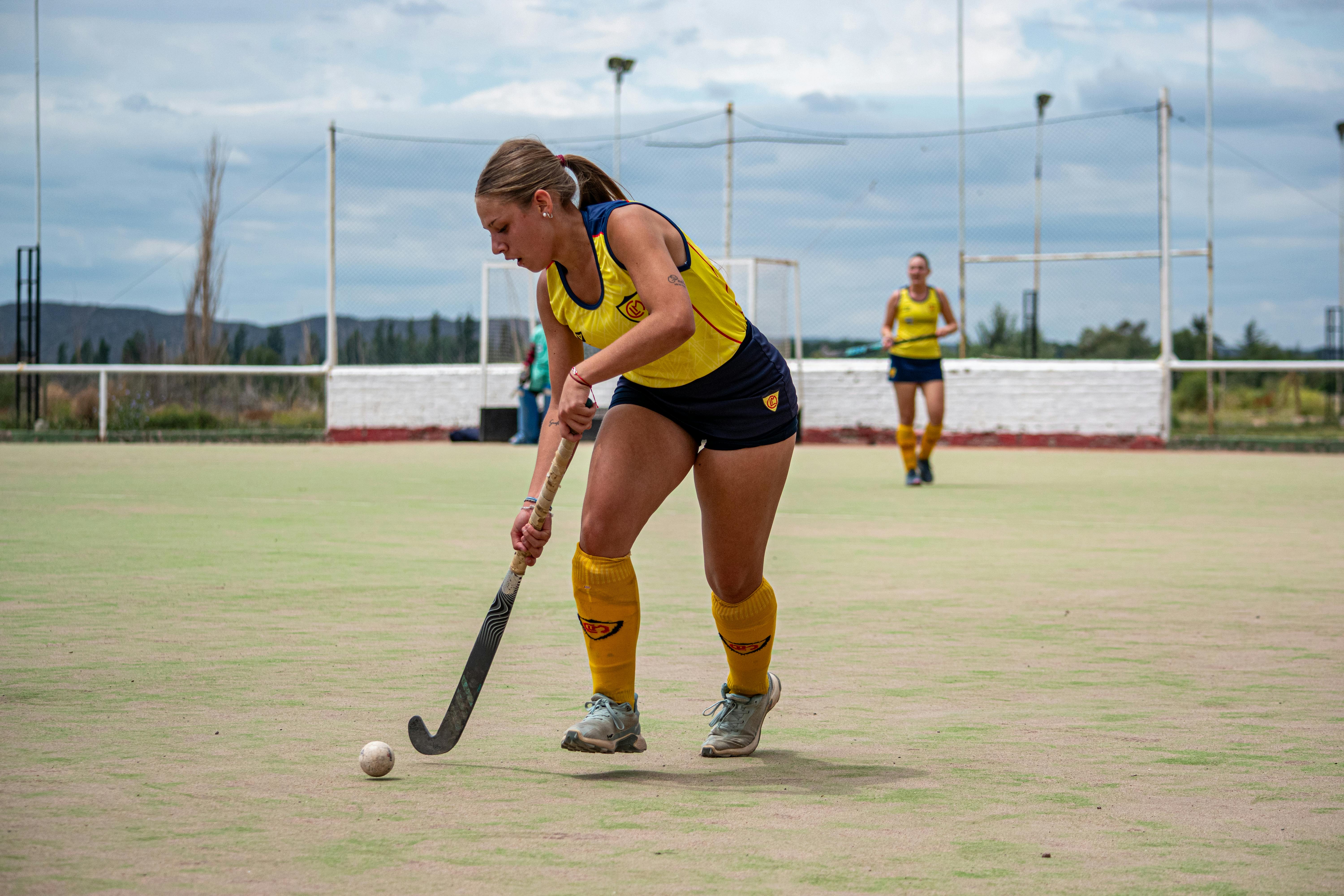 NHL photo featuring Female athlete playing field hockey outdoors on a sunny day, focusing on the game.