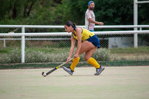Dynamic field hockey scene with female player hitting the ball during a match.