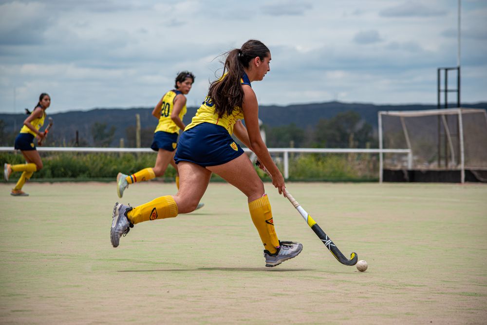 Field hockey players in coordinated match uniforms on an outdoor pitch