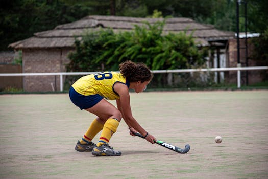 Young woman playing field hockey on an outdoor field. Enthusiastic and focused.
