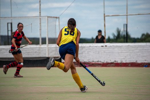 Two female field hockey players competing on an outdoor field.