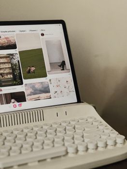 A vintage-style keyboard setup with a tablet displaying social media images, creating a cozy workspace atmosphere.