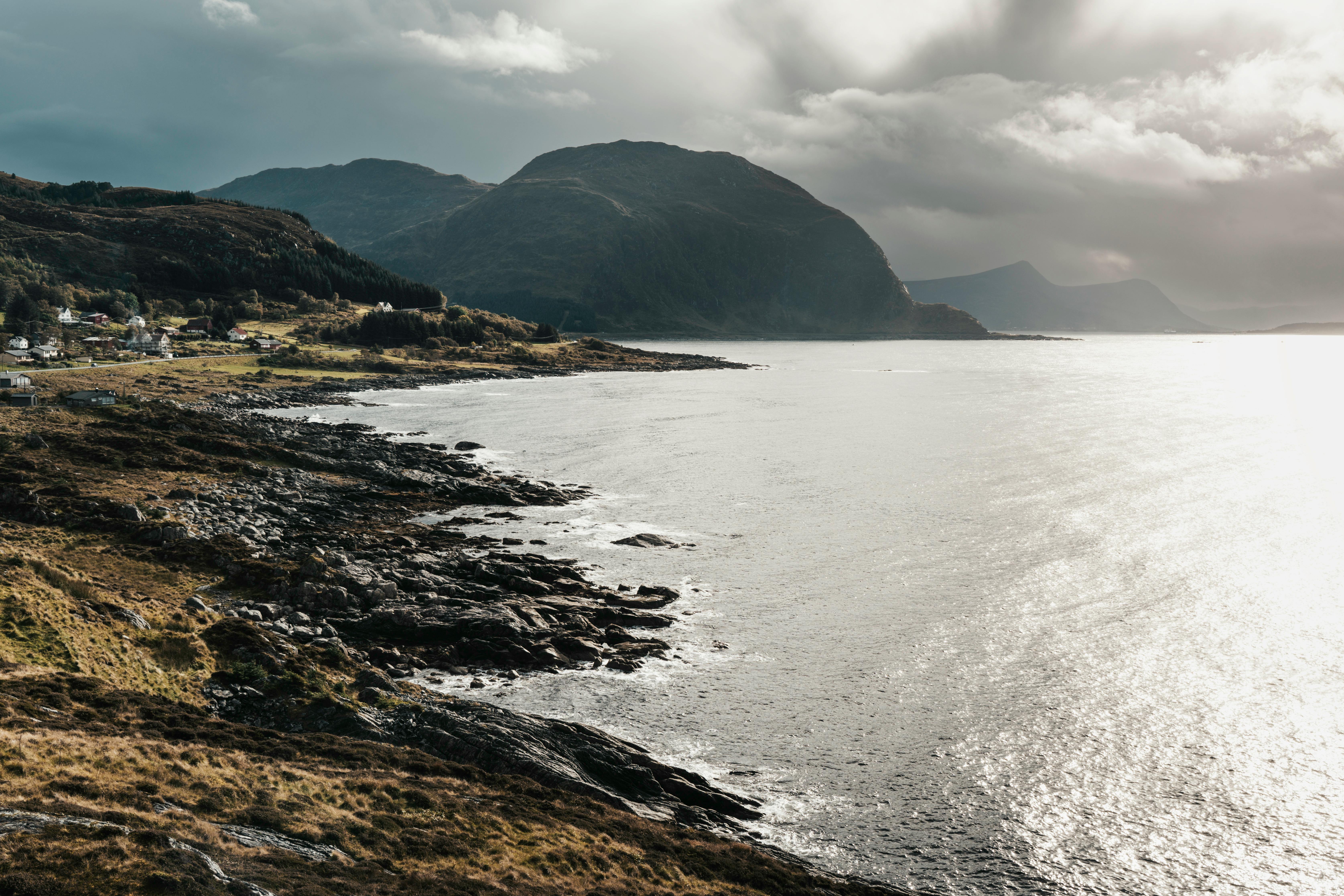 Breathtaking view of a rocky Norwegian coastline with mountains and a cloudy sky.