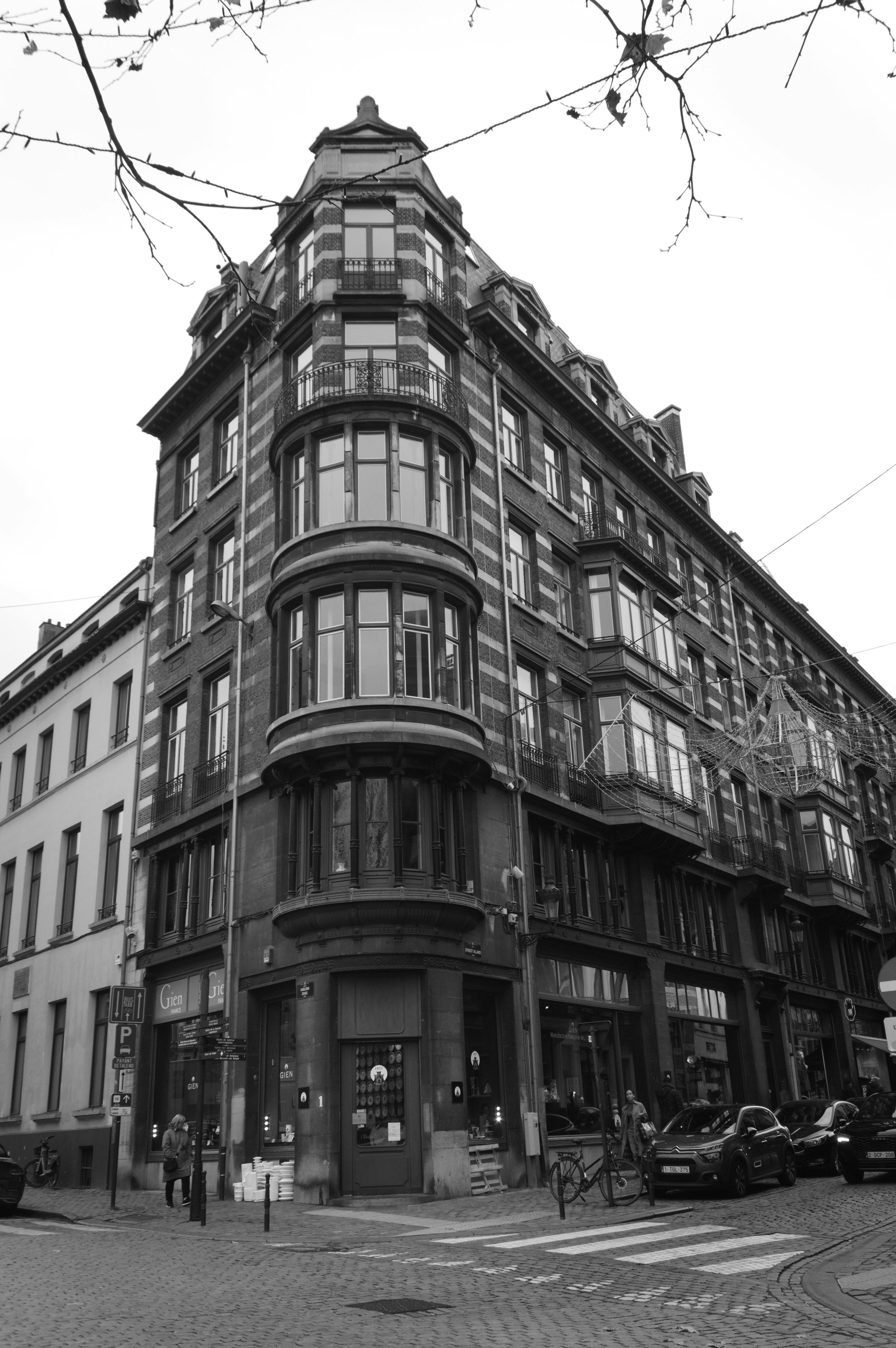 Free Black and white photo of a historic European building on a city street corner. Stock Photo