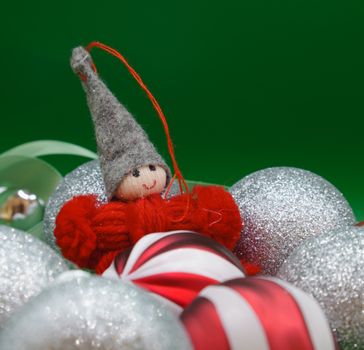 A cheerful elf Christmas ornament surrounded by glittery holiday decorations.