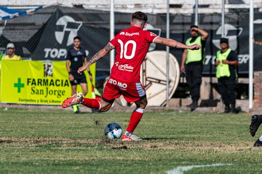Dynamic action of a soccer player in red uniform kicking the ball during a match.