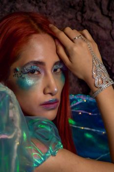 Vibrant mermaid-inspired makeup and fashion portrait with sparkling accessories.