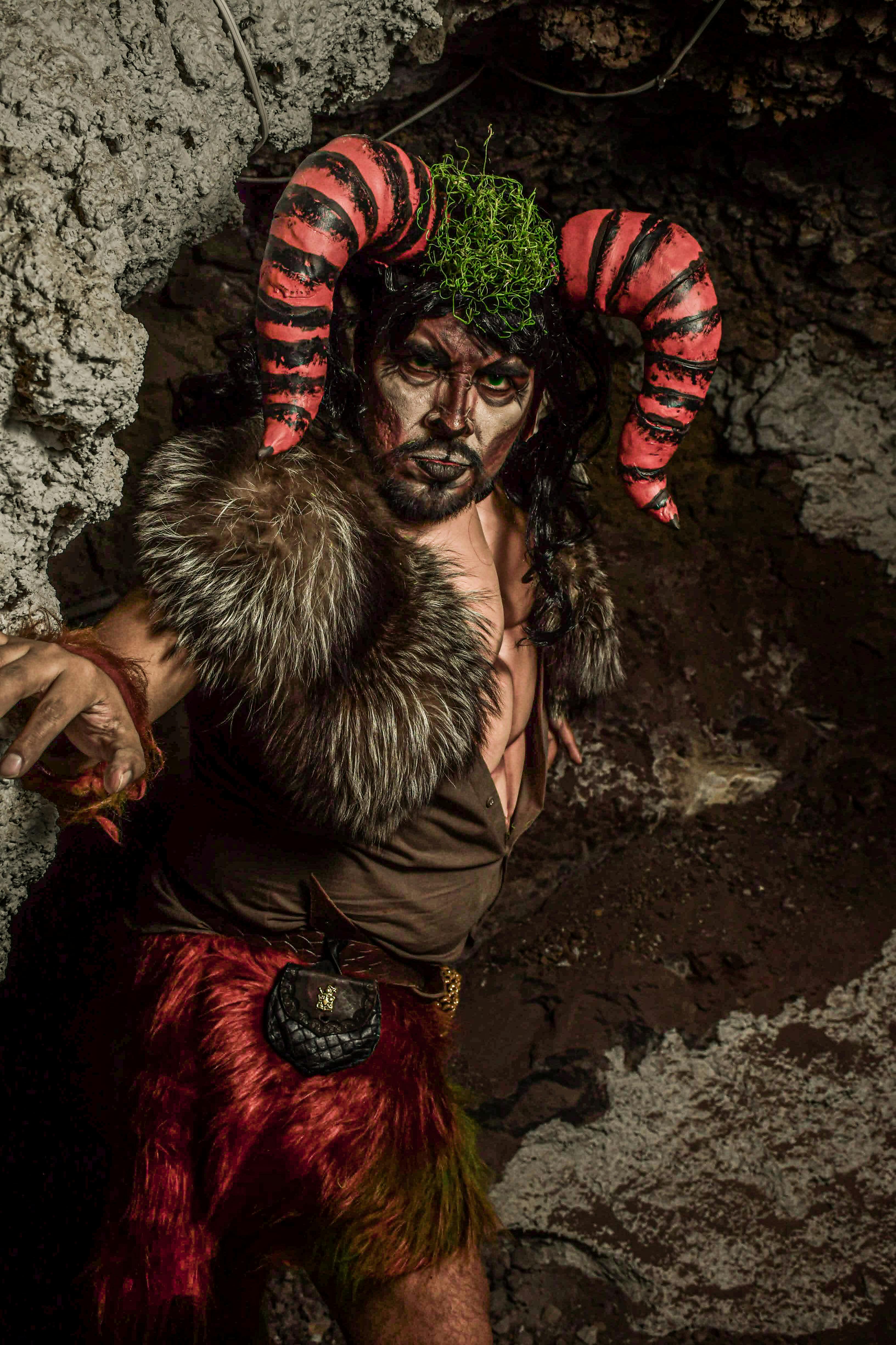 Fantasy-themed portrait of a man in a cave wearing a mythological costume with horns.