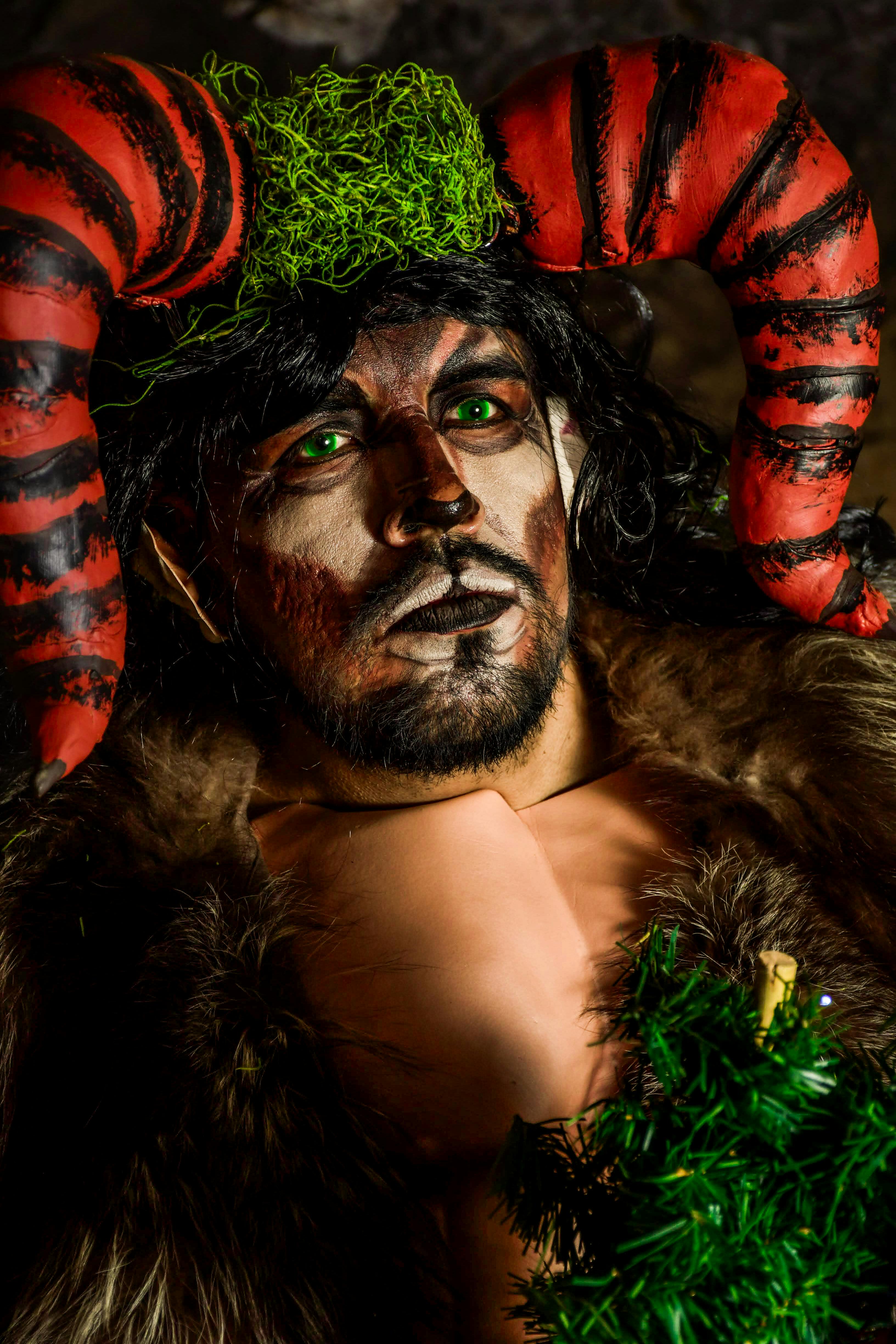 A man in a dramatic festive costume with horns, fur, and face paint, embodying fantasy and creativity.