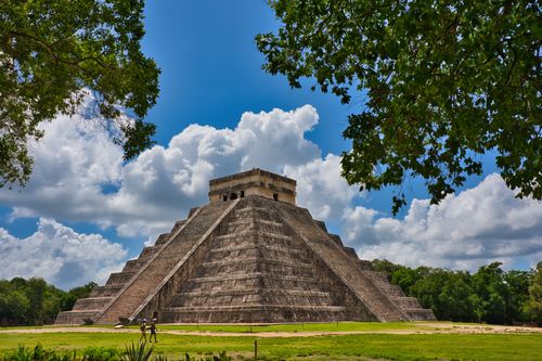 Free Majestic view of El Castillo pyramid in Chichen Itza, under a bright blue sky with vibrant green surroundings. Stock Photo