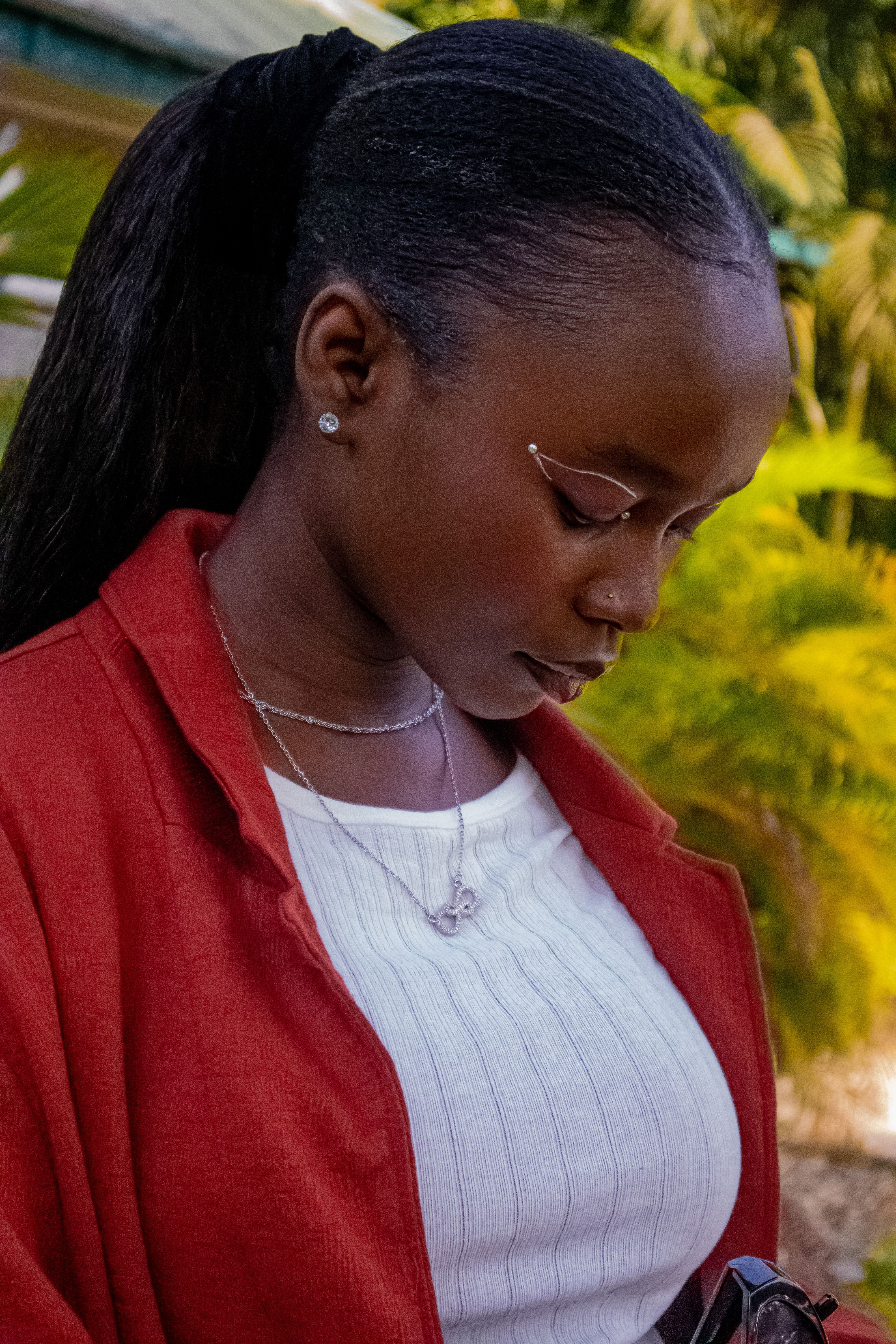 Profile of a fashionable woman outdoors in a red coat, emphasizing elegance and style.