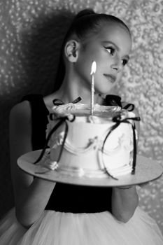 Black and white portrait of a girl holding a birthday cake with lit candles.