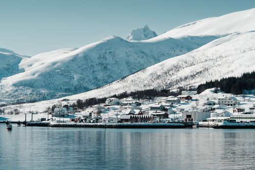 Free Picturesque snow-covered village in Norway under majestic mountains and clear sky. Stock Photo