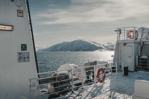 Free Winter landscape from a ferry in Norway with snow-covered mountains and calm sea. Stock Photo