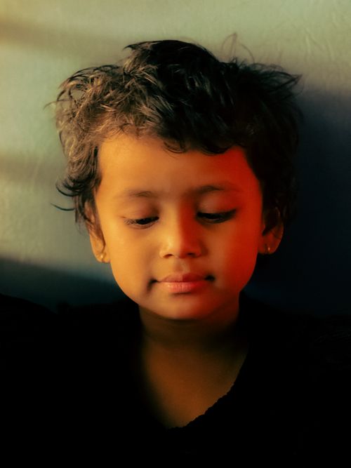 Free A serene portrait of a child with warm, soft lighting and a thoughtful expression. Stock Photo