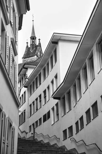 Black and white photo of a narrow alleyway in Basel, Switzerland featuring historic architecture.
