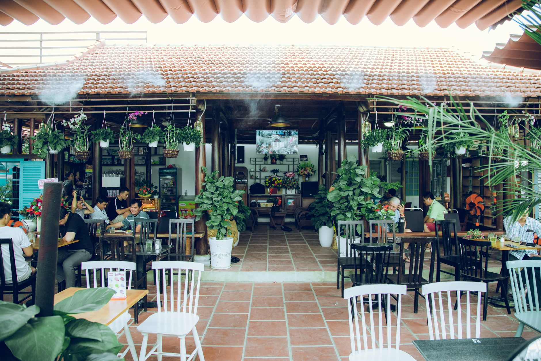 Relaxing outdoor cafe with plants and diners in Ho Chi Minh City, Vietnam.
