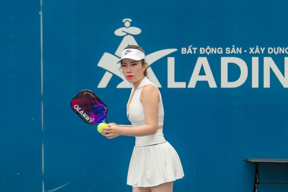 Dynamic image of a female pickleball player ready to serve during a match in Hải Phòng, Vietnam.