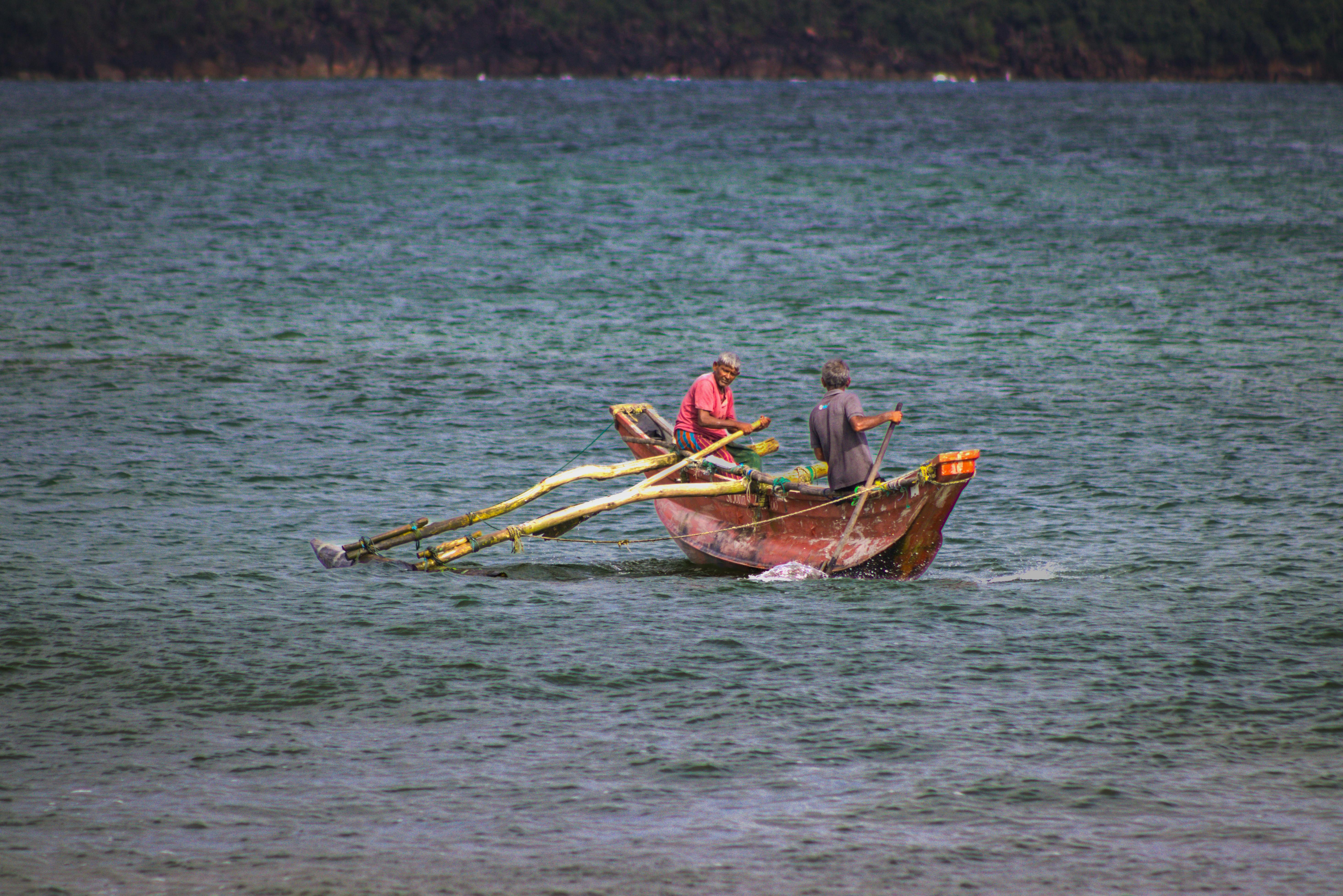 Two fishermen in a traditional boat rowing in Galle, Sri Lanka s ocean waters.