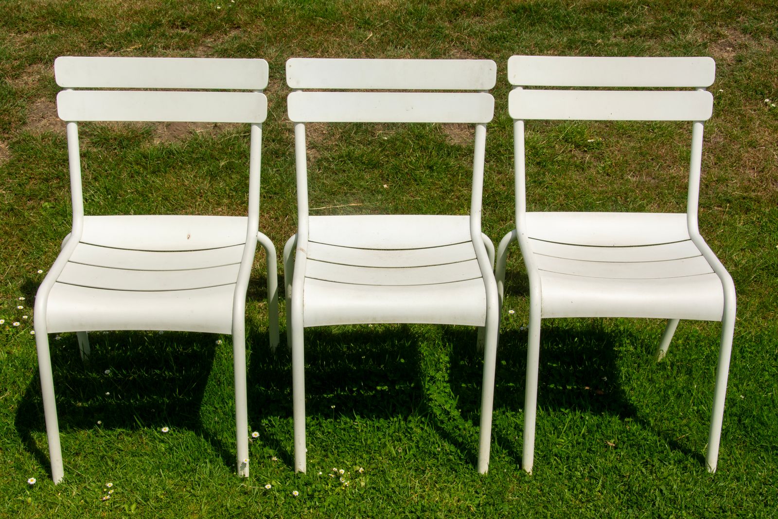 9 Things Master Bird Watchers Never Tell Beginners 2 Three white garden chairs arranged on a fresh green lawn under daylight.