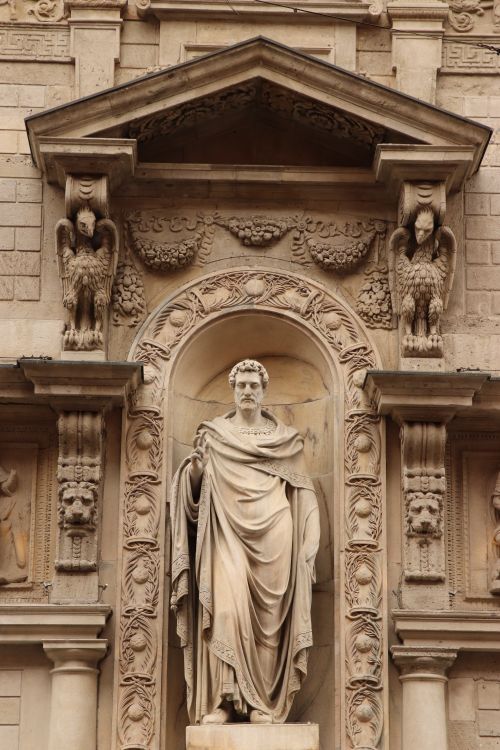 Free Intricate stone statue on a historic Milanese building facade. Stock Photo