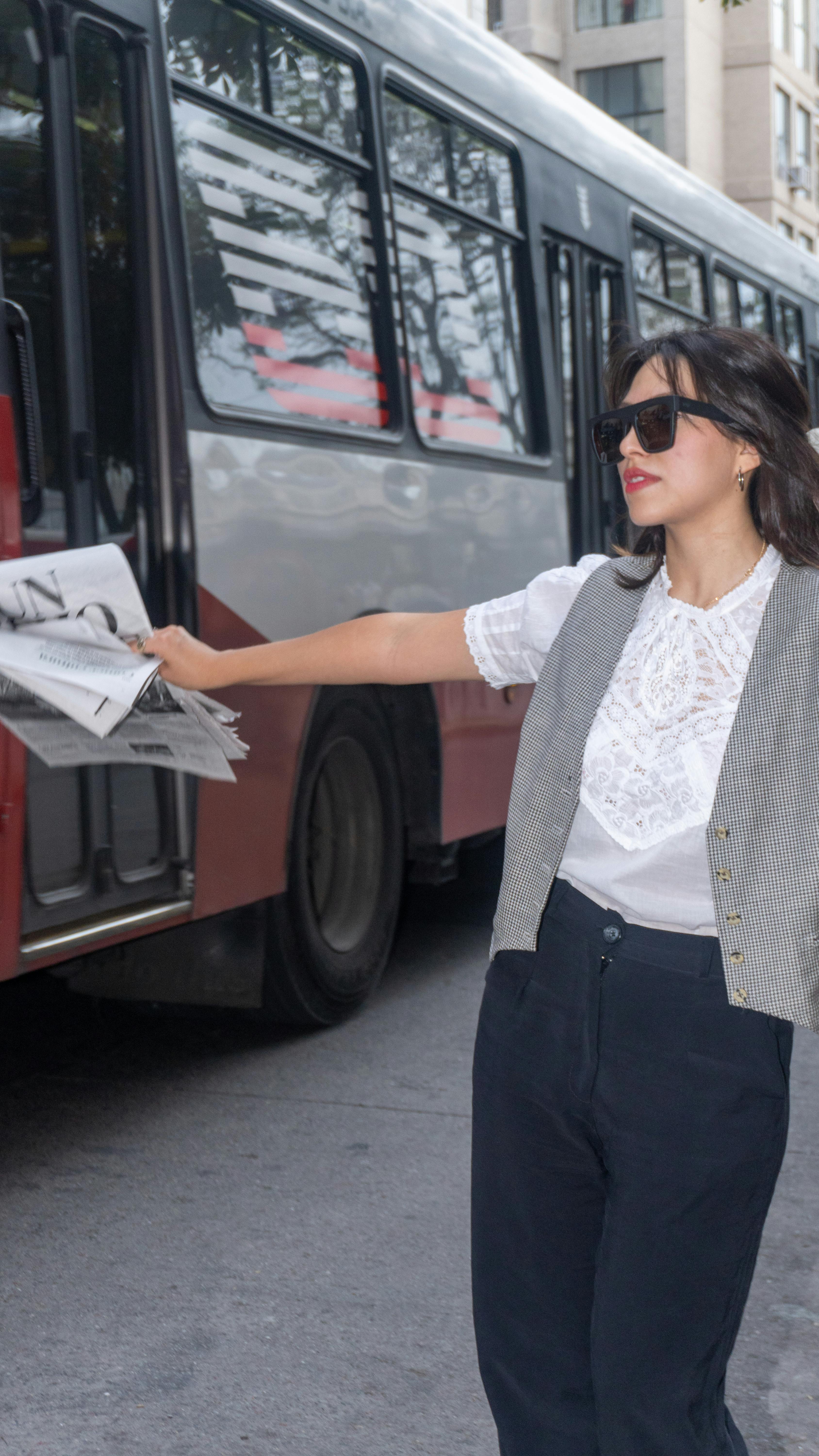 woman boarding bus with newspaper in hand