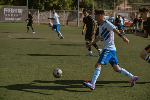 Players engage in a competitive soccer match on a sunny day, showing dynamic teamwork and skill.