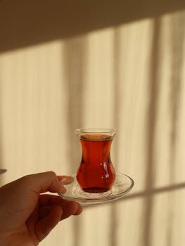 A close-up of Turkish tea in glass cup with sunlit pattern background.