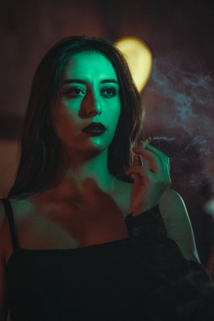 Woman in green light with drifting smoke, photo by AINNNEK on Pexels