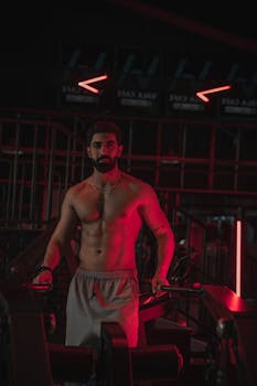 Strong and focused man working out in a modern gym illuminated by red lighting.