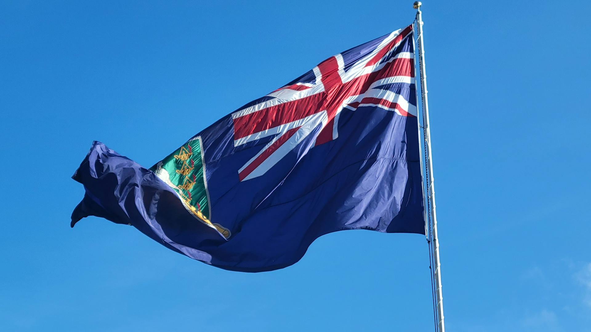 British Virgin Islands flag waving against a clear blue sky, symbolizing national pride.