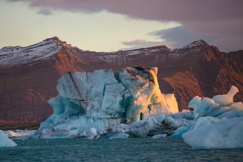 Free Stunning panorama of icebergs in a glacier lagoon with mountain backdrop at dusk, ideal for nature themes. Stock Photo