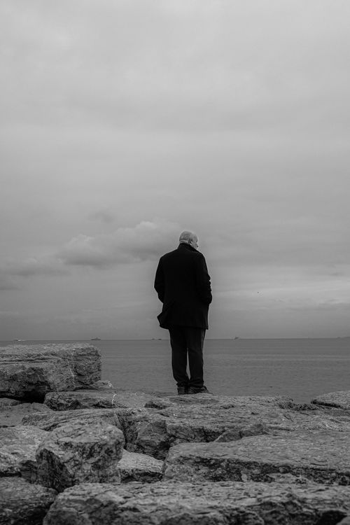 Free A lone man stands on rocks overlooking the Bosphorus in a black and white scene. Stock Photo