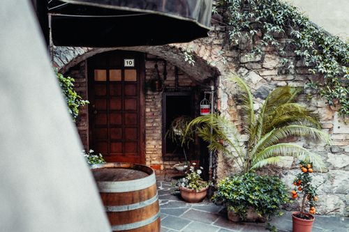 Free Charming rustic courtyard featuring stone walls, lush greenery, and potted plants. Stock Photo