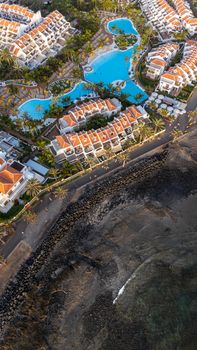 Stunning aerial shot of a seaside resort with pools and villas on the Canary Islands coastline.