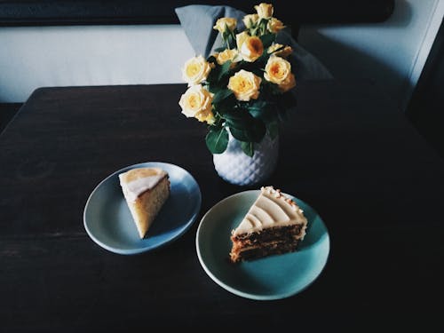 Two Sliced Cakes on Plates Beside Flowers