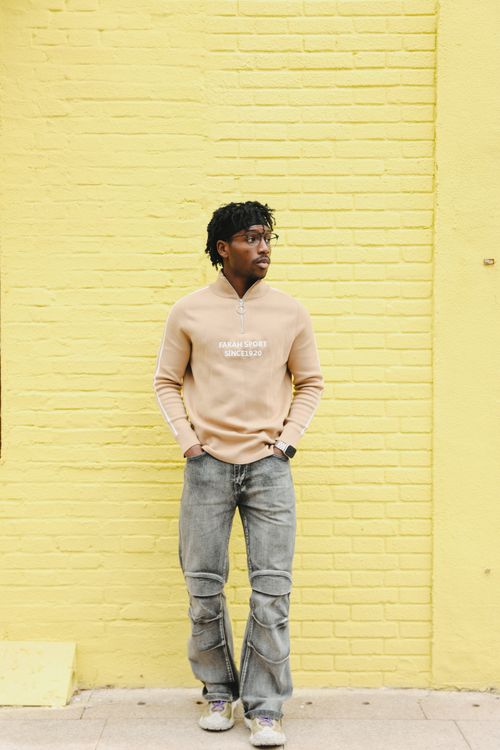 Free Stylish man in casual wear leaning against yellow brick wall outdoors. Stock Photo