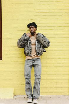 Trendy individual poses with confidence against a vibrant yellow backdrop.