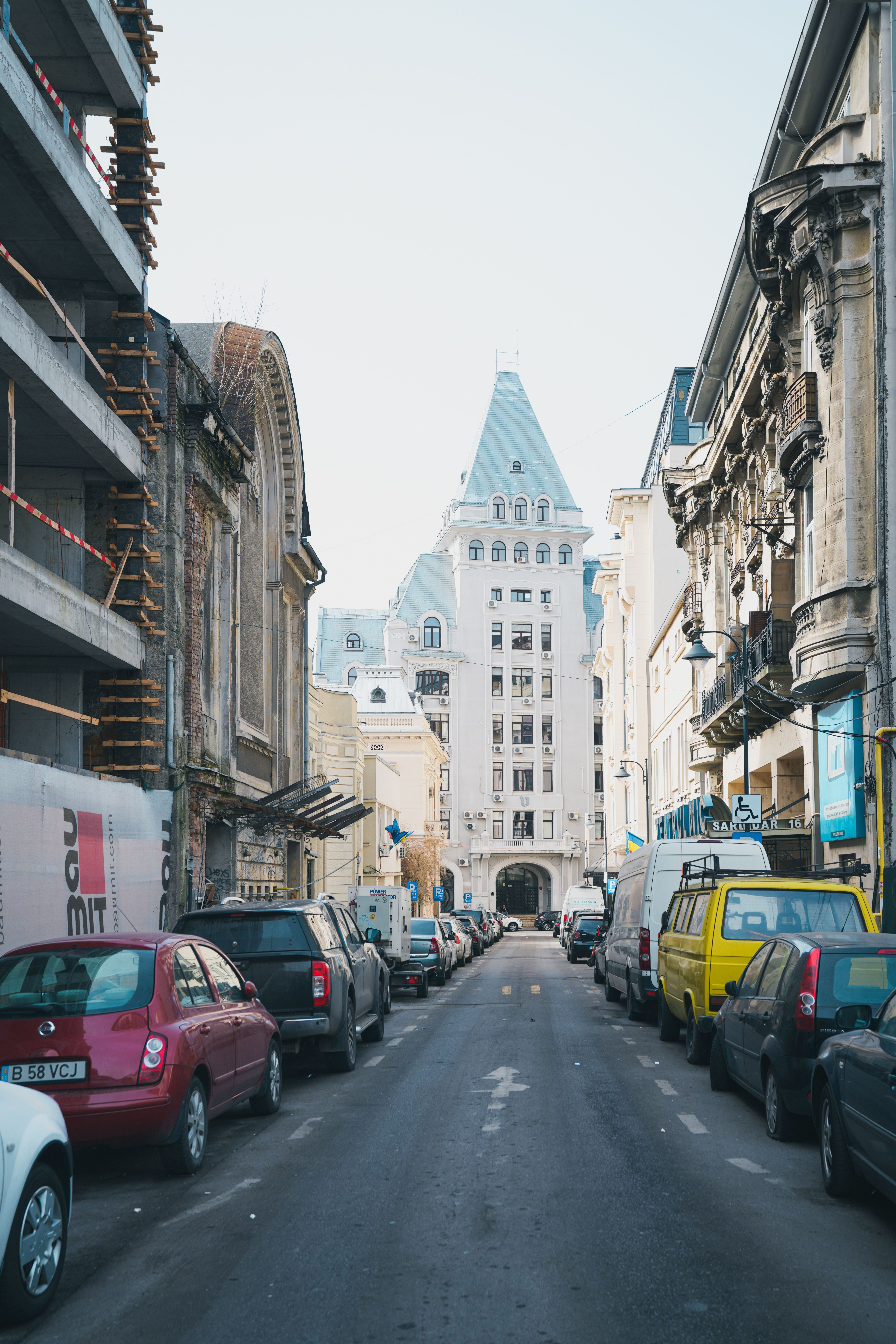 A narrow urban street lined with historic buildings leading to a Gothic architecture landmark.