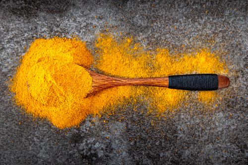 Free Vibrant turmeric powder spread with a wooden spoon for cooking inspiration. Stock Photo