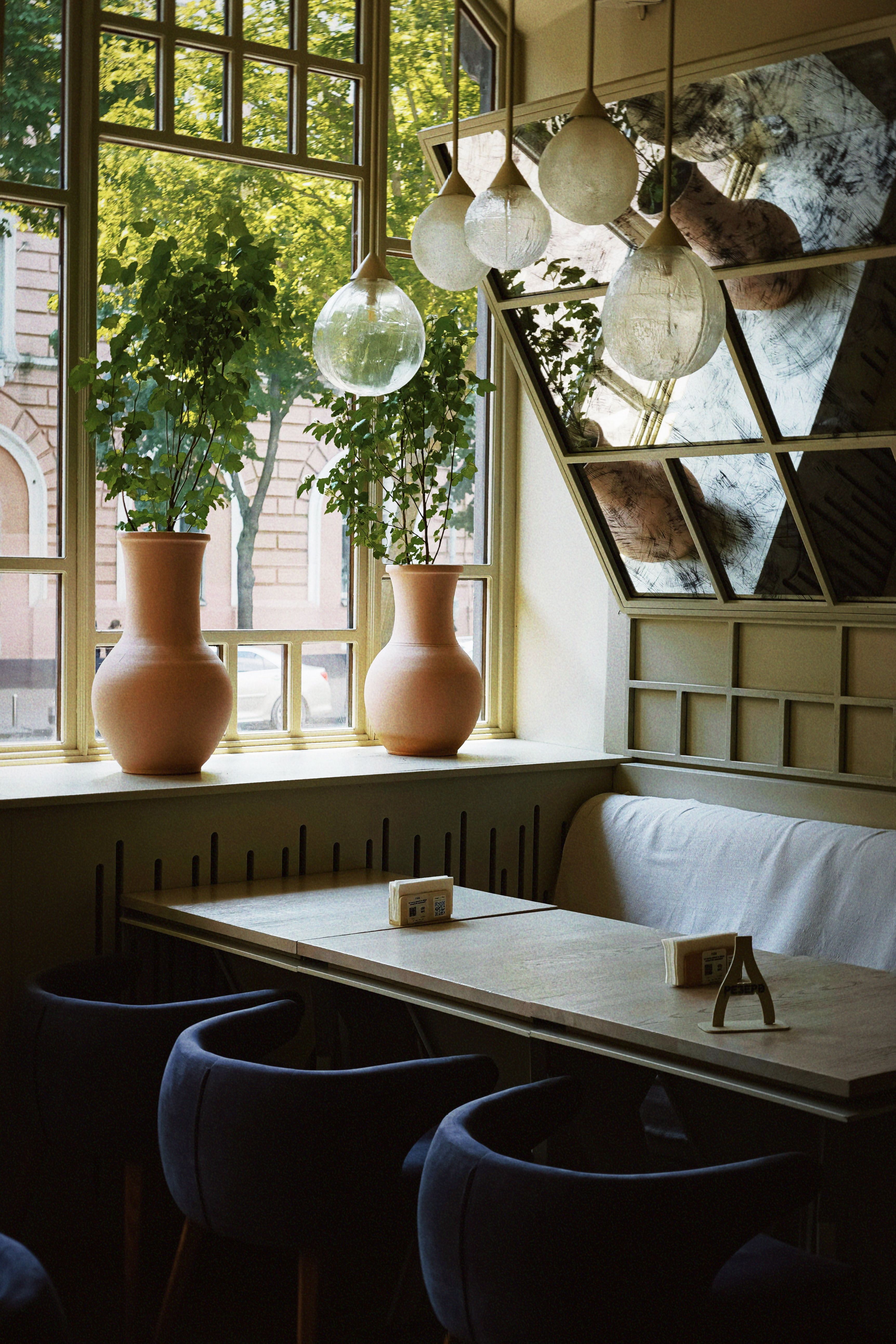 Inviting cafe interior with stylish seating, natural light, and potted plants.