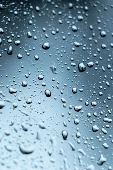 Detailed view of water droplets on glass with a cool blue tone, perfect for background use.
