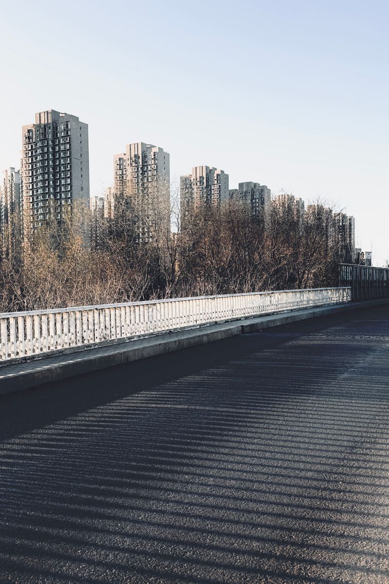 An urban skyline featuring high-rise buildings against a clear blue sky seen from a bridge.