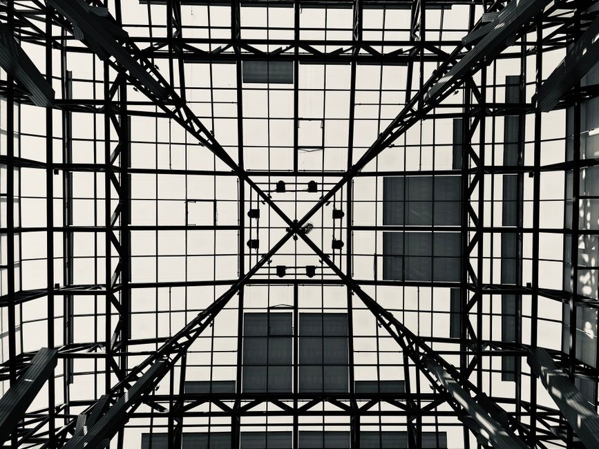 Black and white geometric pattern of a steel and glass ceiling viewed from below.