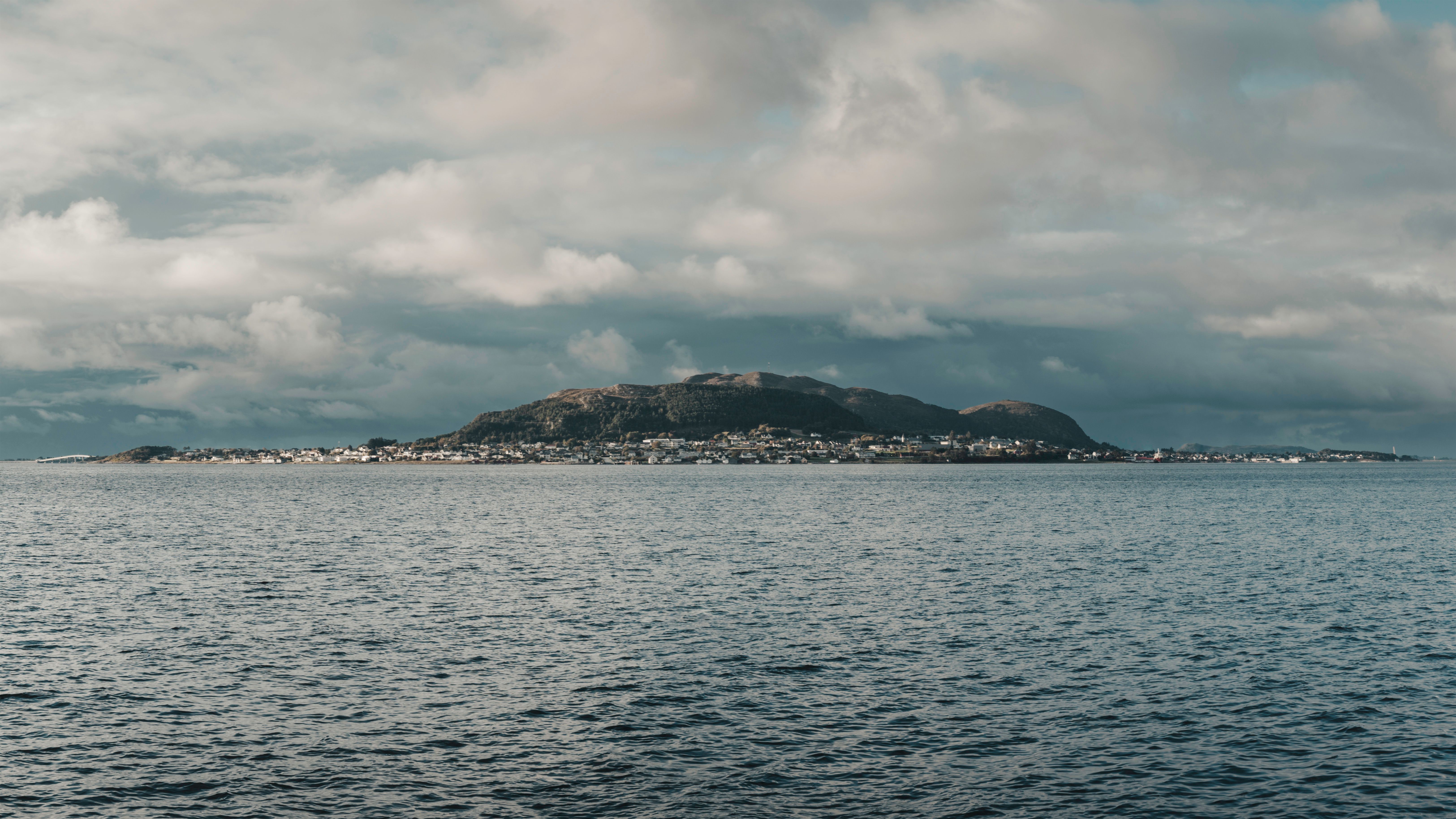 Stunning view of the Norwegian coastline with distant mountains under a cloudy sky.