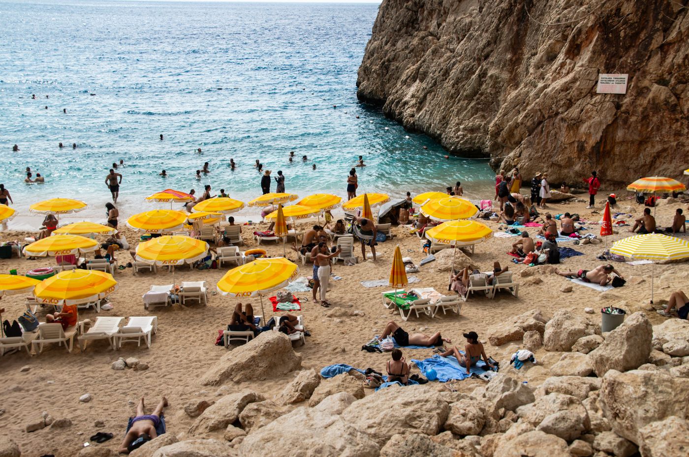Beach visitors relaxing under shelters beside clear coastal water