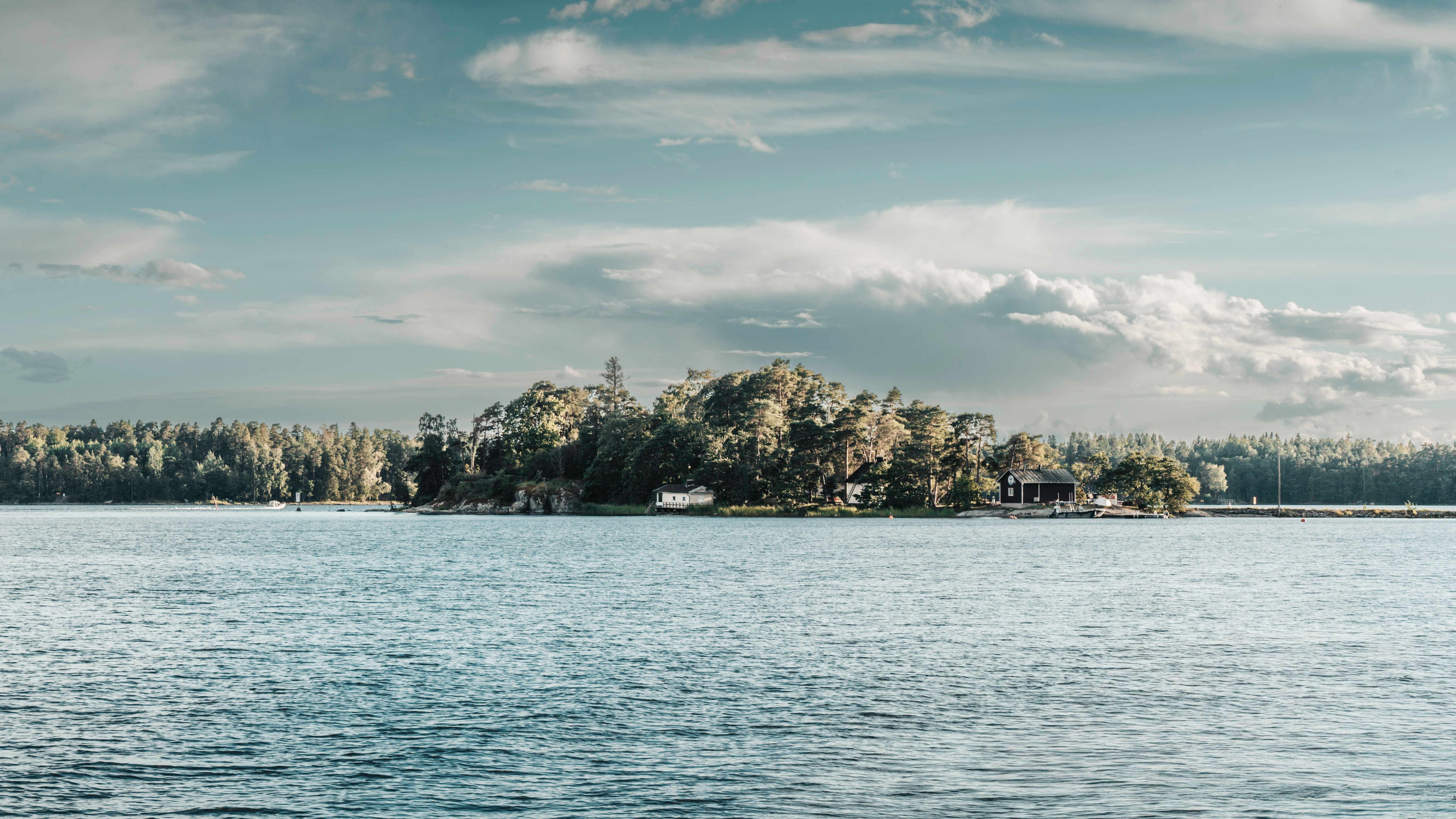 Tranquil Finnish island with lush trees and serene waters under a bright sky.