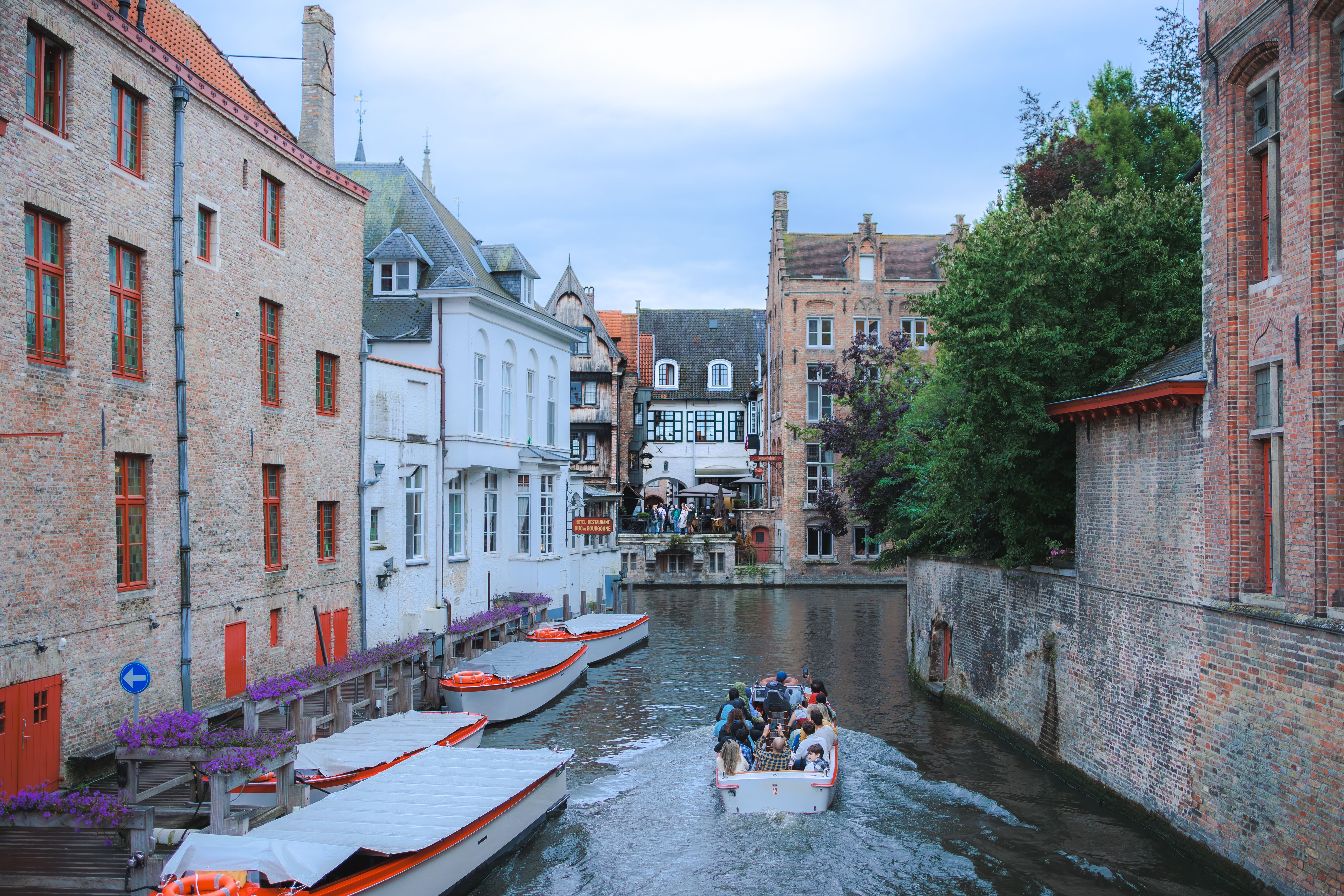 Picturesque canal scene in Bruges featuring historic buildings and a boat tour.